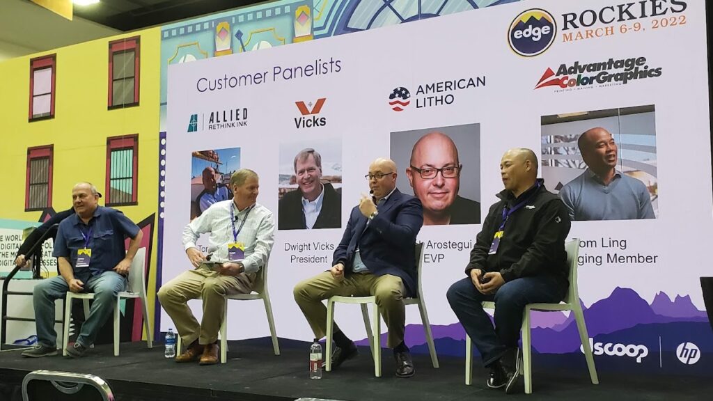 men sitting ion a stage at a trade show