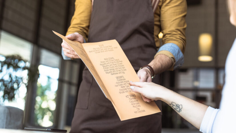 cropped shot of waiter showing menu list to female 2023 11 27 05 06 43 utc scaled